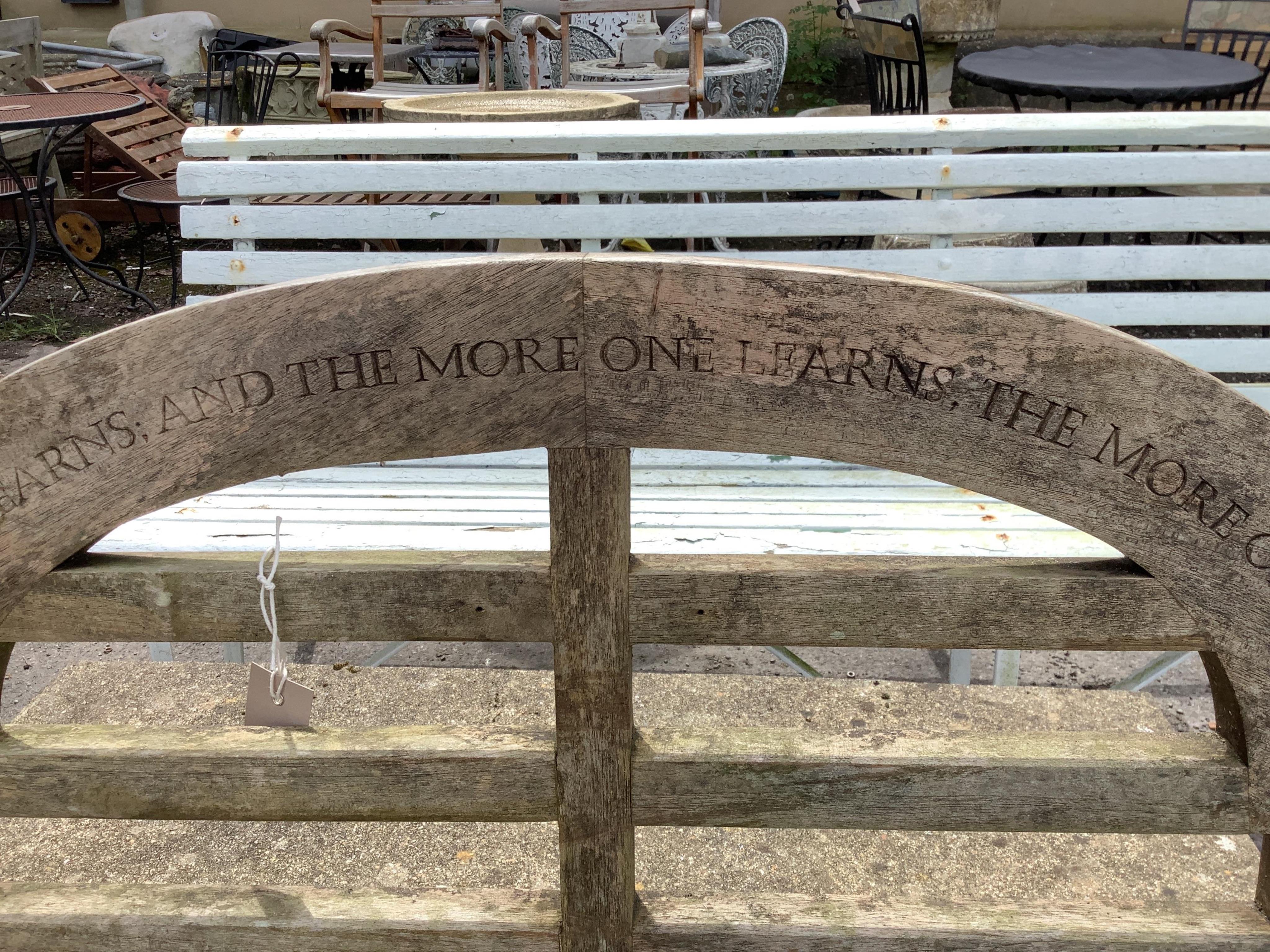 A weathered teak Lutyens style garden bench, with carved inscription, width 55cm, height 106cm